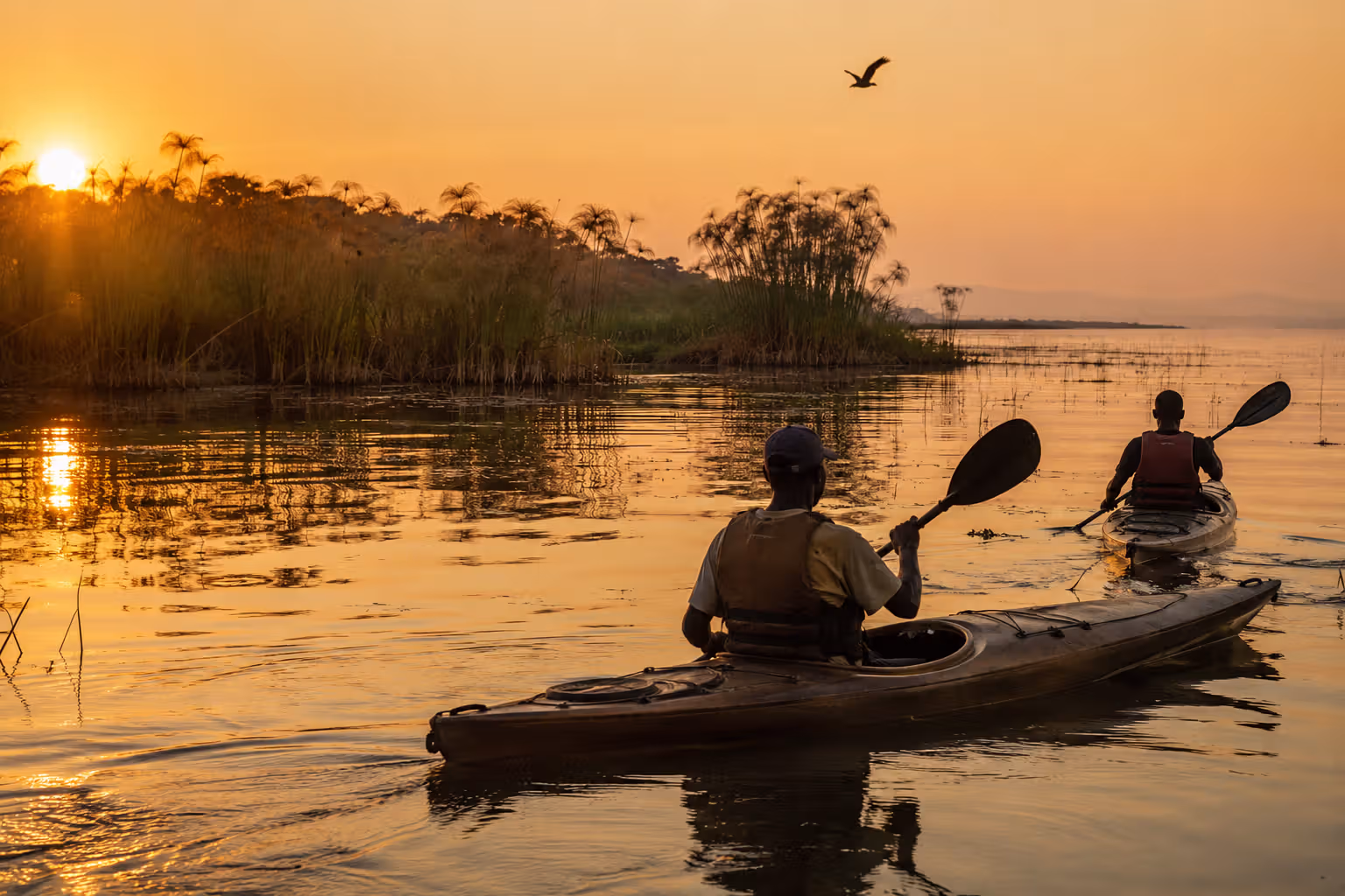 Two kayakers paddling on Lake Victoria at sunrise near Kisumu with a local guide