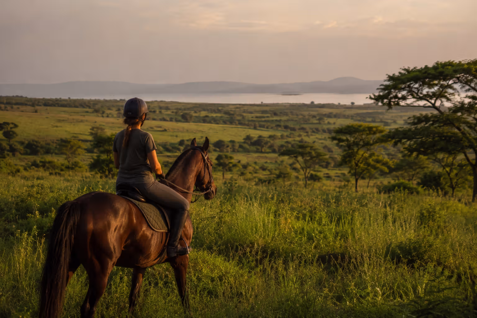 Rider on horseback in open countryside near Kisumu with Lake Victoria in the distance